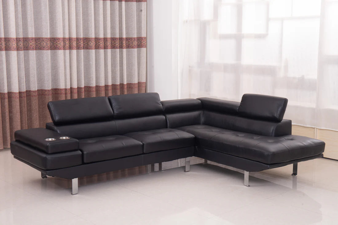 Black leather sectional sofa in a room with curtains and a light floor.