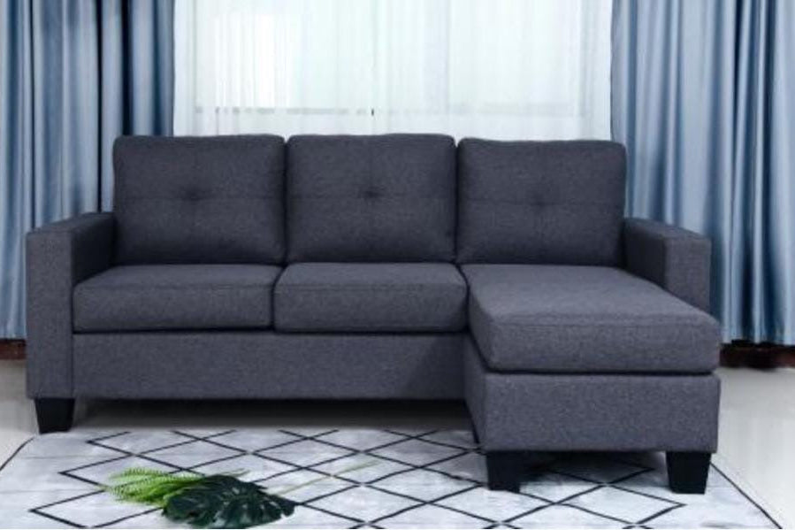 Gray sectional sofa in a room with light blue curtains and a white rug.