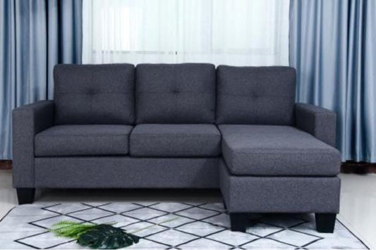 Gray sectional sofa in a room with light blue curtains and a white rug.