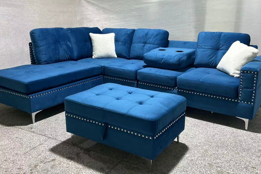 Full view of the Blue Velvet Reversible Sectional Sofa, showcasing the rich, plush fabric and the matching storage ottoman placed next to the chaise.