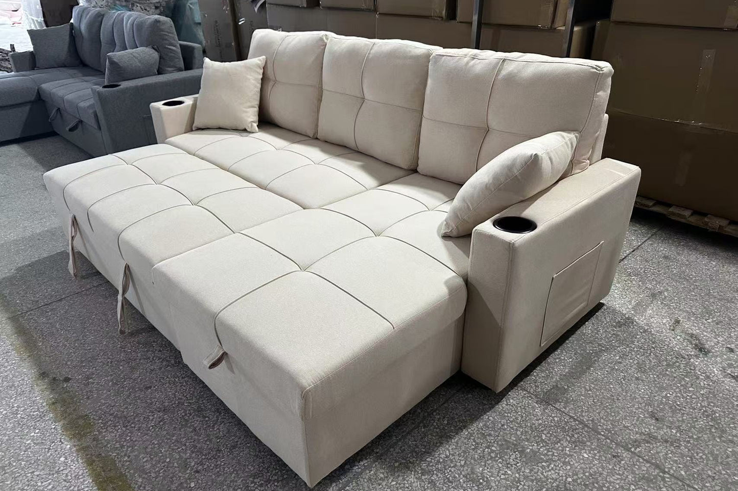 Full view of the Courtney Beige Fabric Reversible Sectional Sofa, showcasing the neutral color and the pull-out sleeper function ready for use.