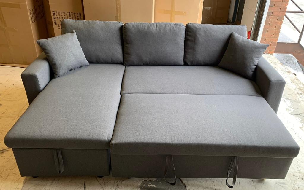 Close-up detail illustrating the smooth pull-out mechanism of the sleeper bed hidden beneath the Grey Fabric sectional seating.