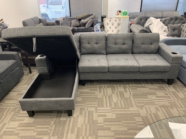 Close-up view of the center console showing the dual cup holders and the open chaise revealing the large internal storage compartment.