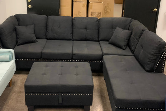 Full view of the Snow Black Linen Sectional Sofa, showcasing the textured dark fabric and the matching storage ottoman placed next to the reversible chaise.